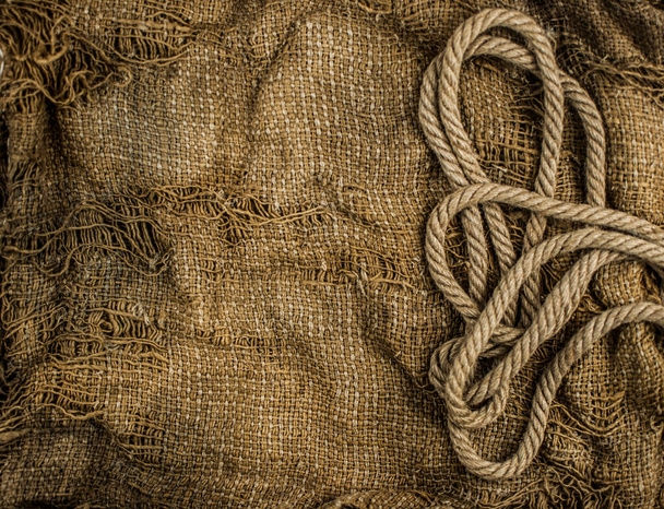 Hemp rope on burlap. Close-up of a natural rope and fabric. Calm nice background. - Фото, изображение