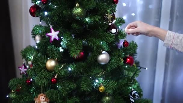 Die Frau schmückt den Weihnachtsbaum mit Kugeln. - Filmmaterial, Video
