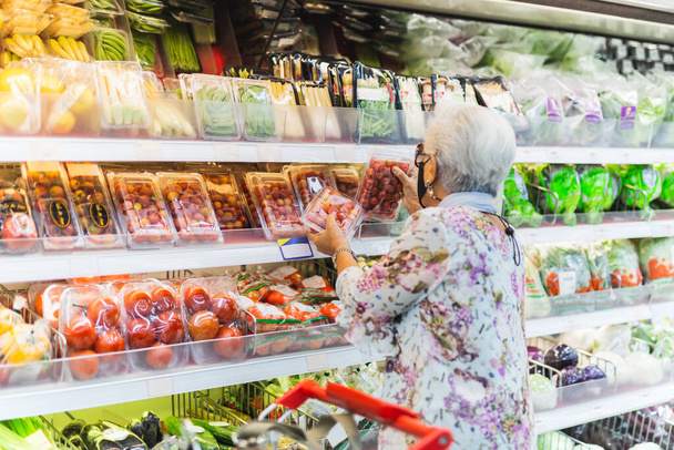 Koruyucu maskeli bir kadın süpermarkette market alışverişi yapıyor. - Fotoğraf, Görsel