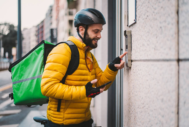 Food delivery rider on his bicycle. Image of a middle age man at work in the city center. Delivering pizza and burgers at home with the thermal backpack - Foto, immagini