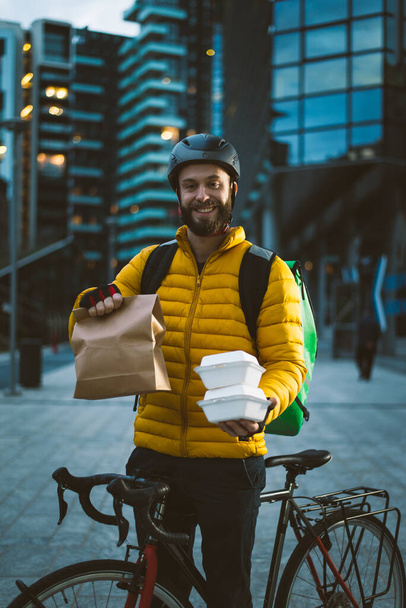 Jinete de reparto de comida en su bicicleta. Imagen de un hombre de mediana edad trabajando en el centro de la ciudad. Entrega de pizza y hamburguesas en casa con la mochila térmica - Foto, imagen