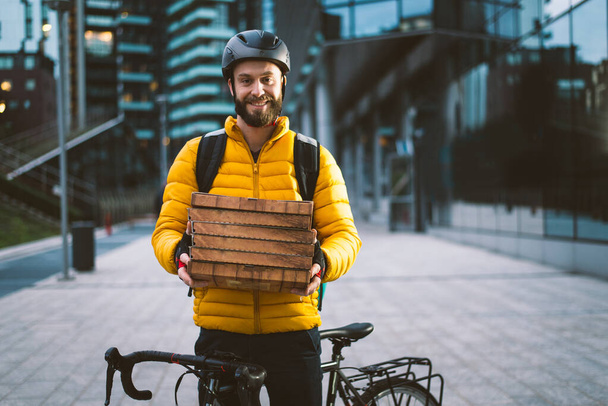 Ведучий доставки їжі на велосипеді. Зображення чоловіка середнього віку на роботі в центрі міста. Доставка піци і бургерів в домашніх умовах з термальним рюкзаком
 - Фото, зображення