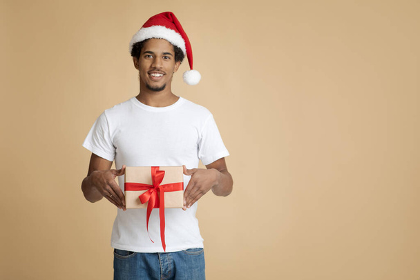 Mann Weihnachtsmann hält Schachtel mit Schleife zur Überraschung für Frau zu Neujahr oder Weihnachten in der Urlaubspackung - Foto, Bild