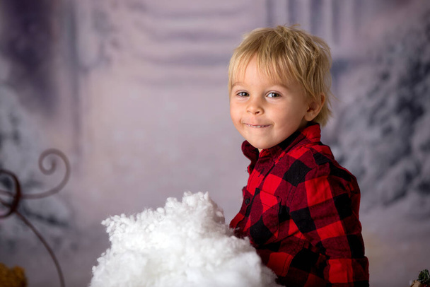 Cute toddler boy with winter outfit, playing in the snow, christmas studio shot - Fotó, kép