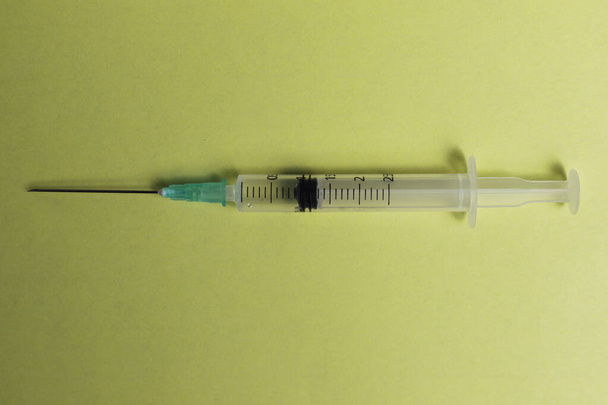 Seringue hypodermique sur fond jaune Concept de médecine, vaccination, covide-19, sars-cov-2 - Photo, image