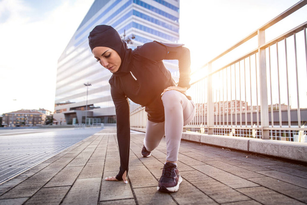 Muslim urban runner training in the city center. Beautiful woman doing sport in the early morning - Foto, Bild