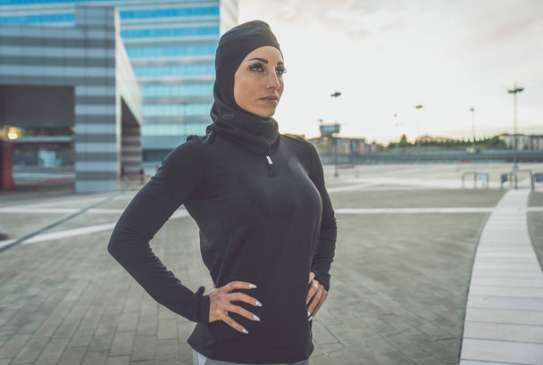 Muslim urban runner training in the city center. Beautiful woman doing sport in the early morning - Фото, изображение