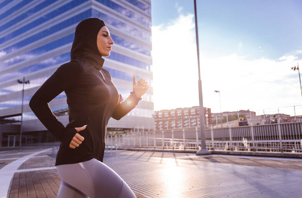 Muslim urban runner training in the city center. Beautiful woman doing sport in the early morning - Φωτογραφία, εικόνα