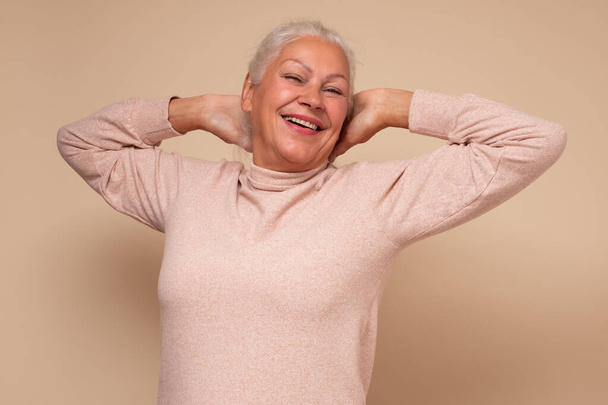 Задоволена старша жінка підняла розтягнуті руки, відпочиваючи у вихідні
 - Фото, зображення