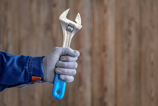 Pán drží v ruce nastavitelný zámečnický klíč s modrou rukojetí. Zámečnická oprava - Fotografie, Obrázek