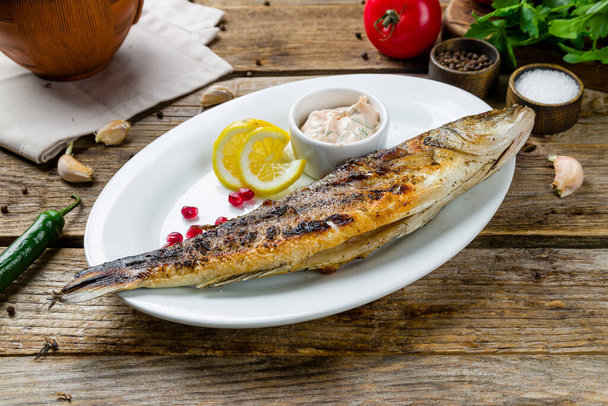 Fried sea bass on plate with lemon slices  - Photo, Image