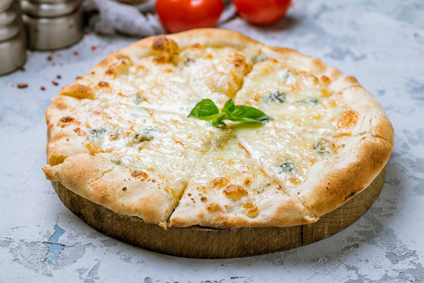 tasty pizza with cheese and bail leaves and red tomatoes on wooden table surface  - Фото, зображення