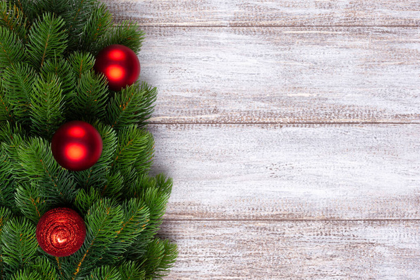 Noel ağacının dallarındaki üç kırmızı top ahşap arka planda, Noel kartı. - Fotoğraf, Görsel