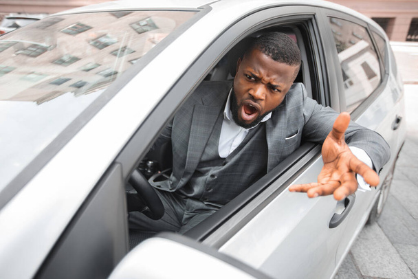 Жахливий чорний бізнесмен жестикулює і кричить під час водіння автомобіля
 - Фото, зображення