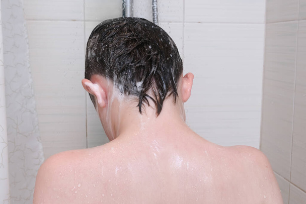 Hygienic procedures and healthy habits of a preteen boy - taking shower and washing hair with shampoo. - Фото, зображення