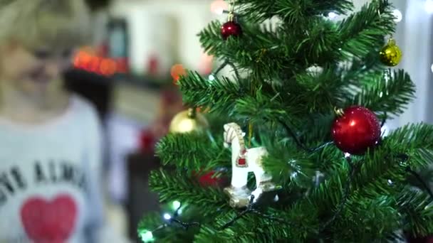 クリスマスのおもちゃは若い女性によって装飾されているクリスマスツリー上の馬をロッキング. - 映像、動画