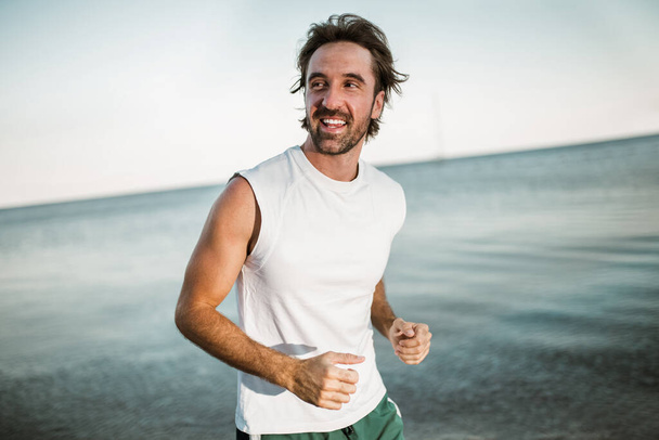 Futó férfi kocog a parton. Férfi futók tréning kívül edzés. - Fotó, kép