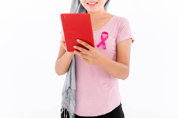 Asyalı kadınlar üstlerine pembe kurdele takarlar. Beyaz arka planda kırmızı tablet kullanıyor. Göğüs kanseri kavramı, kanser önleme kavramı. - Fotoğraf, Görsel