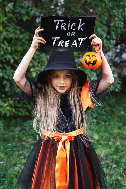 Little girl in Halloween costume trick or treating outdoor - Foto, afbeelding