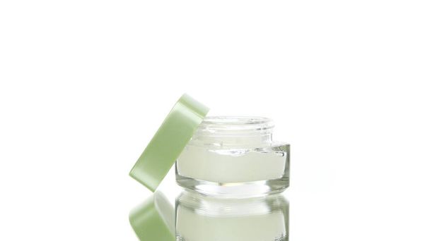 Βάζο καλλυντικών Skincare γυάλινο με ενυδατική κρέμα περιστρεφόμενη σε λευκό φόντο - Φωτογραφία, εικόνα