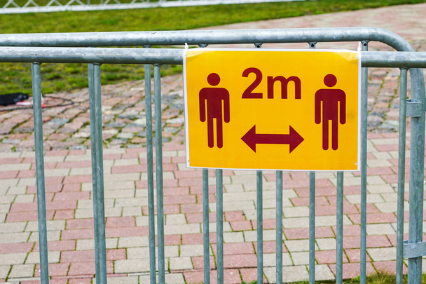a metal barrier with a pictogram for keeping a distance of two meters during the coronavirus - Photo, Image