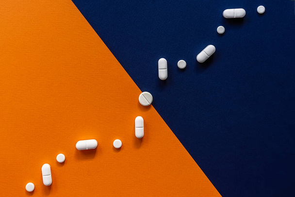 Colorful blue orange background with white pills in the form graph. Medical concept of a health, pharmacy and healthcare - Fotografie, Obrázek