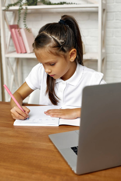 little child girl using laptop for online lesson at home - Foto, immagini