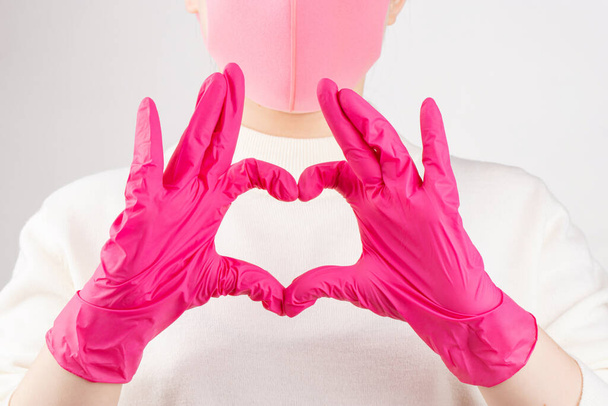 niña en guantes de color rosa y máscara sobre un fondo blanco - Foto, imagen