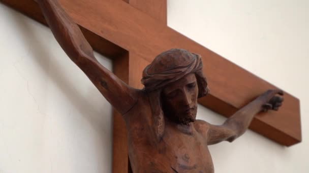 Drewniany posąg Jezusa Chrystusa Ukrzyżowanie na białej ścianie w kościele, ozdoba ukrzyżowanego Jezusa z wieńcem cierniowym na głowie i krople krwi. Syn Boży umierający na krzyżu za ludzkie grzechy, Jezus cierpiący na - Materiał filmowy, wideo