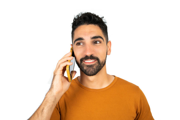 Portrait of young latin man talking on the phone against white background. Communication concept. - Fotó, kép