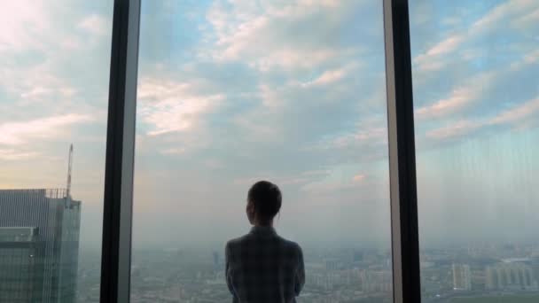 Takaisin näkymä mietteliäs nainen katselee kaupunkikuva ikkunan läpi pilvenpiirtäjä - Materiaali, video