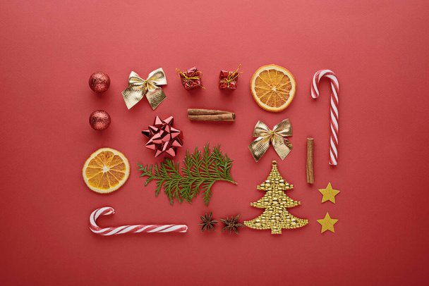 Christmas composition. Candy, decorations, toys on red background, top view, flat lay festive new year background - Photo, Image