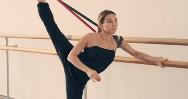 Балерина растяжения с помощью резистентной ленты холдинг бар - Кадры, видео