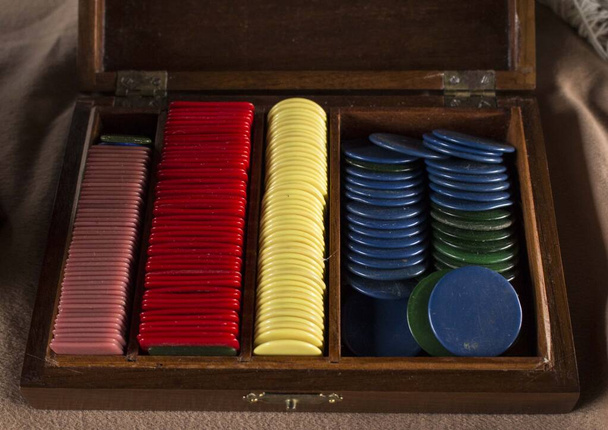 Wielokrotność plastikowych żetonów pokerowych (lub używane do innej gry) wewnątrz piękne stare drewniane pudełko wykonane. Różne kolory żetonów ułożone razem - Zdjęcie, obraz