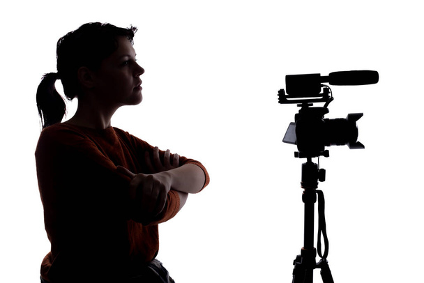 Silhouette of a female indie filmmaker, online content creator or casting director with a camera and mic okking stressed out - Фото, изображение