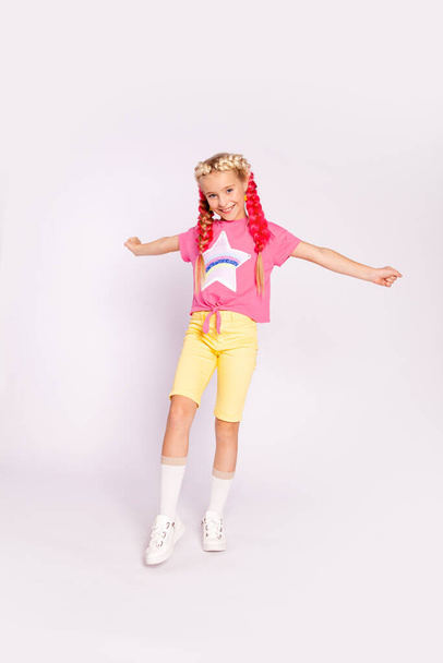 Tyttö kirkkaissa värikkäissä vaatteissa ja värillisillä punoksilla - Valokuva, kuva