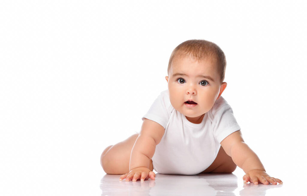 Surprised baby kid creeping on white studio floor - Fotó, kép