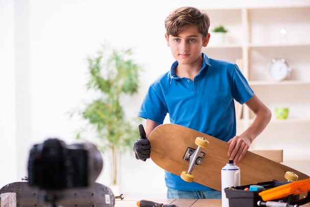 Junge repariert Skateboard und nimmt Video für seinen Blog auf - Foto, Bild