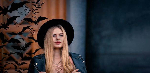 Νεαρή όμορφη ξανθιά στο καπέλο Halloween στο παρασκήνιο και νυχτερίδες του μυστικιστικού κάστρου. Banner με χώρο αντιγραφής - Φωτογραφία, εικόνα