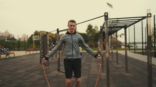 An athlete learns to jump rope on a city outdoor sports ground. Fast calorie burning cardio exercise. Man on urban outside gym workout and fitness jumping rope. Sport, training and lifestyle concept - Footage, Video