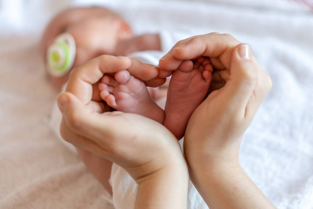 Mother holding baby feet in heart shape - Фото, зображення