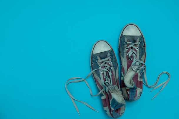 Close up worn and torn sneakers isolated on blue background. Top view and copy space. - Photo, Image