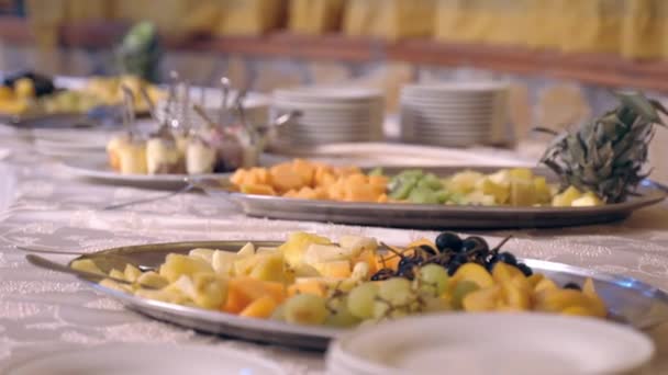 Assortiment van vers fruit gesneden en gesneden voor ceremonie banket partij, mooie catering banket service decoraties met vers fruit vol vitaminen. Druiven, ananas, appel en andere toetjes in - Video