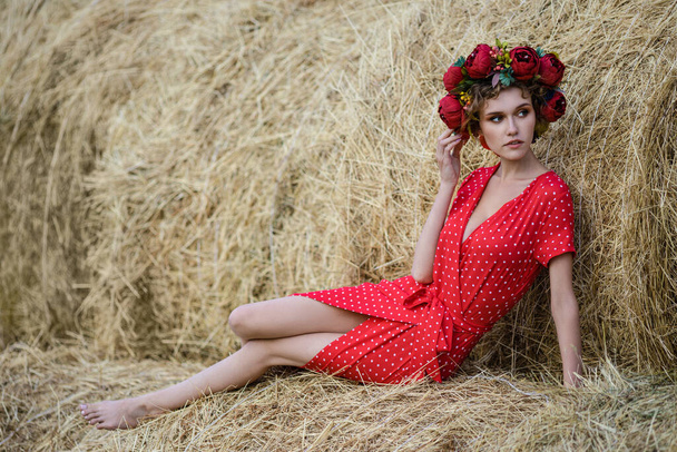 Portrait of a beautiful young model in red dress have fun, posing against on haystacks in sunny autumn day . Autumn warm photo - Foto, afbeelding