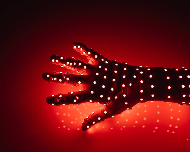 mano humana cubierta con luces led rojas, fondo iluminado - Foto, Imagen