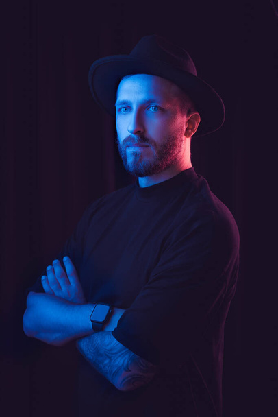 Fashionable guy. Studio shot in dark studio with neon light. Portrait of serious man - Zdjęcie, obraz