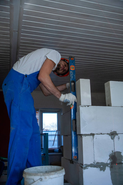 Mason alinhando bloco de concreto autoclavado aerado da parede da casa construída - Foto, Imagem