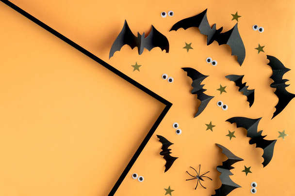 Halloween frame template with black paper bats and plastic spooky eyes on a colored yellow background. - Fotó, kép