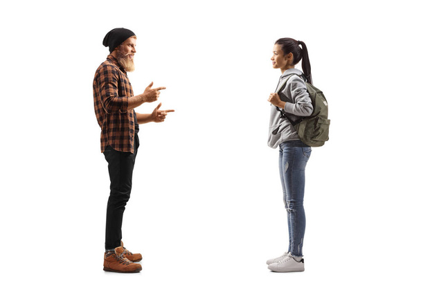 Full length profile shot of a bearded guy standing and talking to a young female student isolated on white background - Zdjęcie, obraz