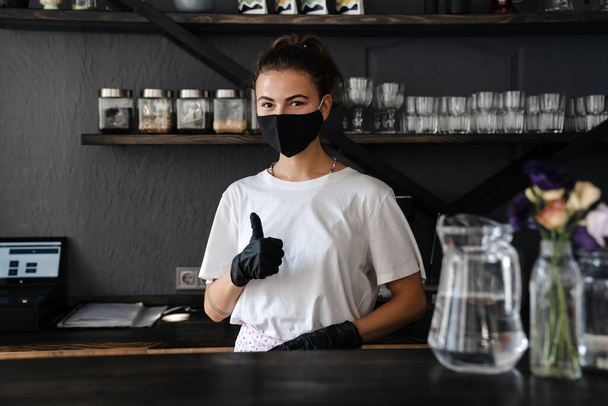 Business owner and barista wearing face mask and smiling after reopening coffee shop - Fotografie, Obrázek